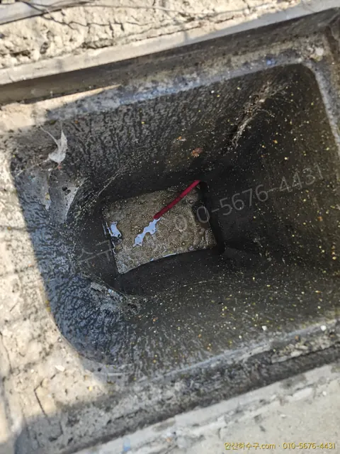 안산 원시동 공장 맨홀 내부에 기름과 이물질이 두껍게 굳어 있는 모습 — 안산하수구 고압세척 전 점검