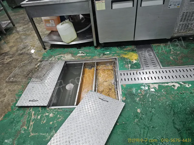식당 주방 바닥 트렌치 덮개를 열고 내부 기름 슬러지를 확인하는 정기 배관세척 점검