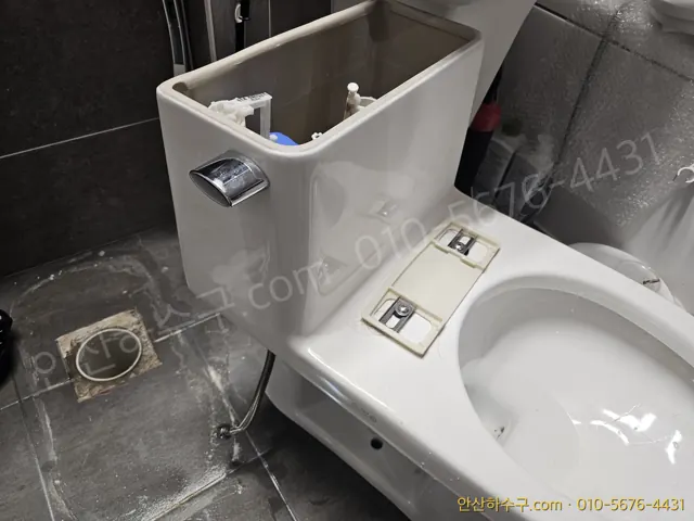 물탱크 뚜껑을 열고 변기 바닥 접합부와 배관 위치를 확인하는 안산 화장실 — 변기 교체 전 바닥 배관 상태 점검