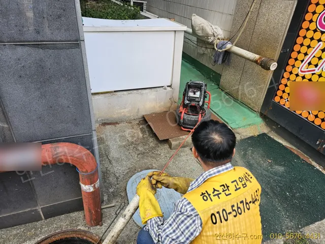 안산하수구 노란 조끼 작업자가 맨홀 앞에서 배관 내시경 모니터로 하수관 내부를 확인하는 모습